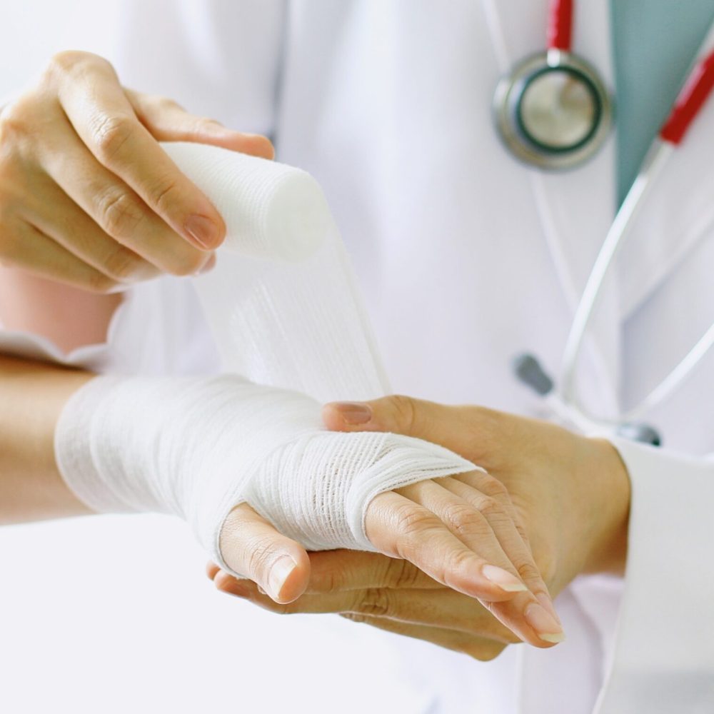 Close-up of female doctor with stethoscope bandaging hand of patient. (Selective Focus)