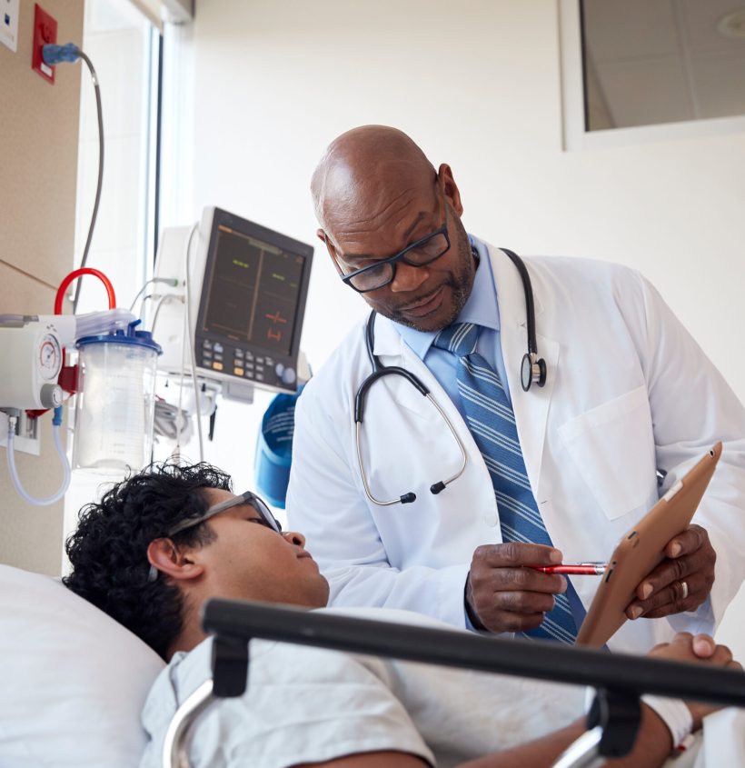 Patient talking to doctor while lying on hospital bed