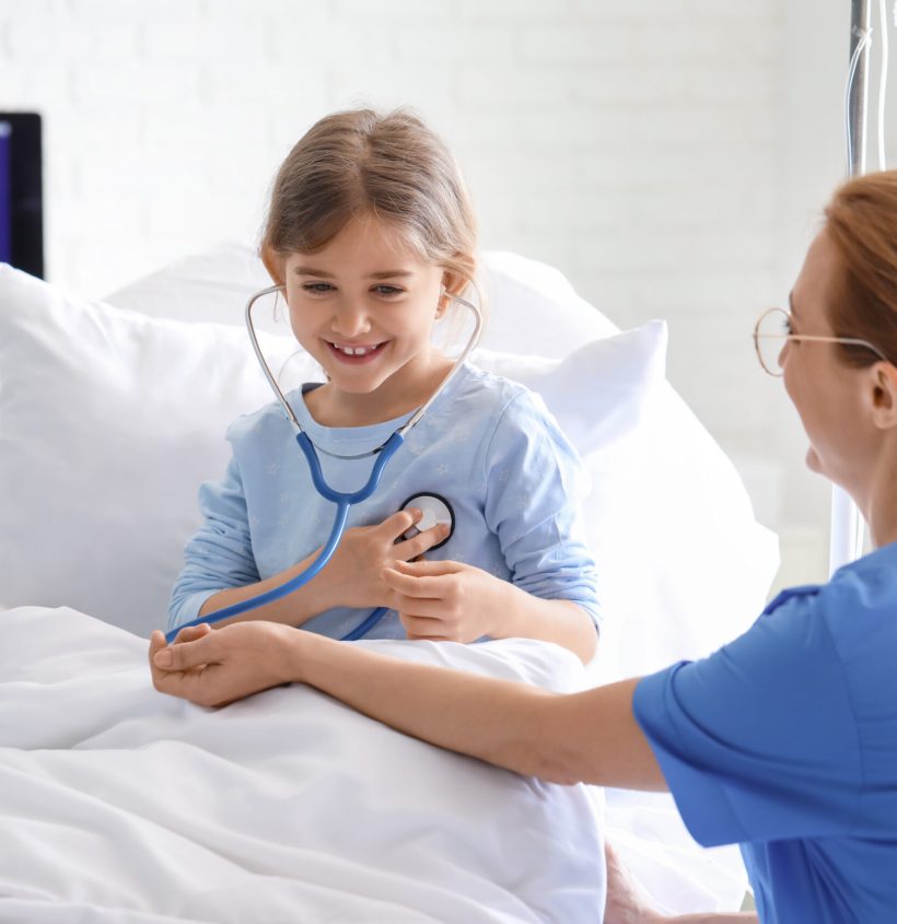 Female doctor working with little girl in hospital room