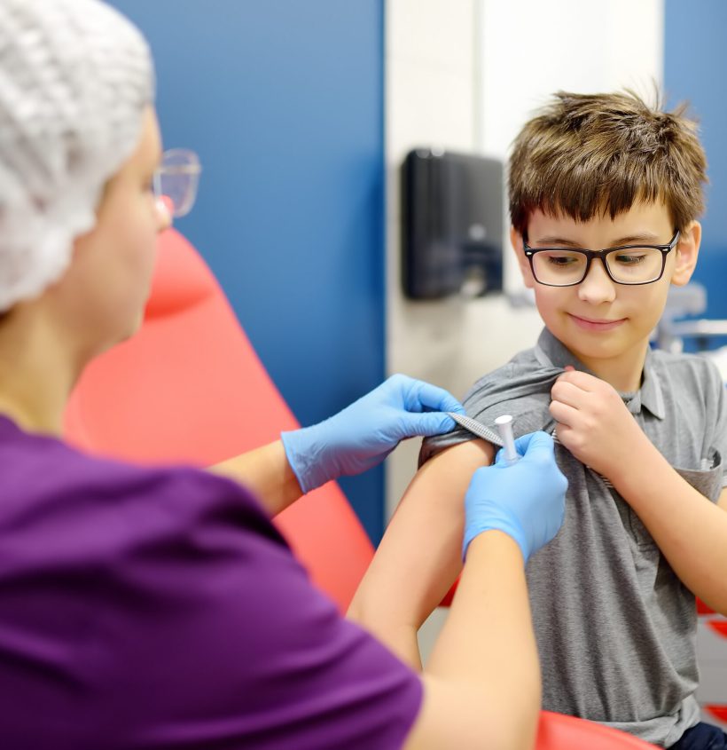 A boy is being vaccinated. A child is given a vaccine during an epidemic or outbreak of a disease. A kid during routine vaccination